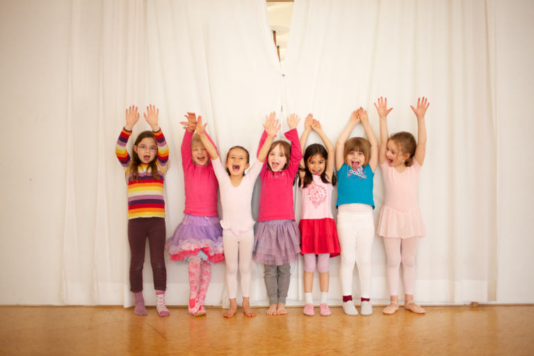 Fröhliche Kinder recken die Hände in die Höhe